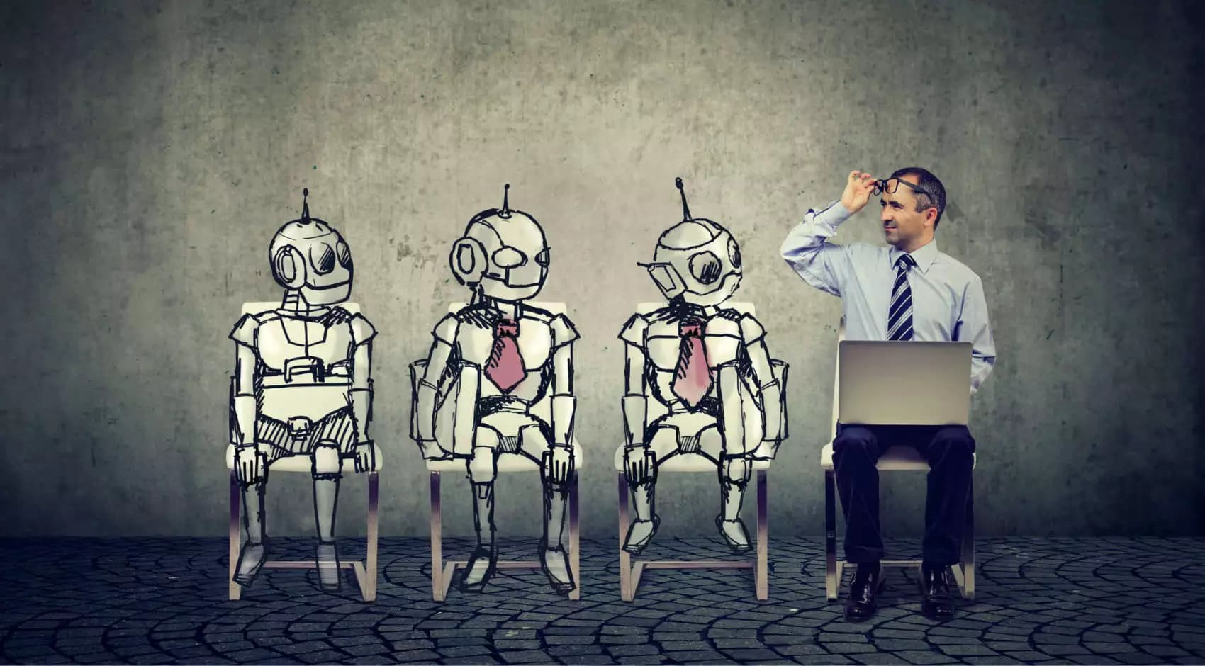 A man in business attire with a laptop sits among three sketch-like robots wearing ties, symbolising humans working alongside artificial intelligence.